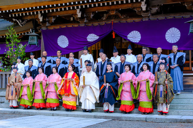 神社の本殿の前で整列する神職と行列の方々